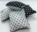 Three small fabric square pillows with black and white polka dot patterns, arranged on a white textured surface against a white background.