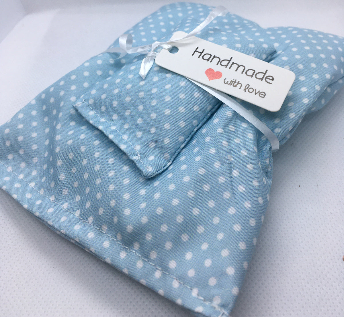 blue miniature duvet set with white spots  and pillow wrapped in a white ribbon and a card saying "Handmade with love" and a little red heart . on a white background.