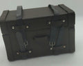 A miniature black toy chest with faux-leather straps and silver-tone rivets, photographed on a light gray background.