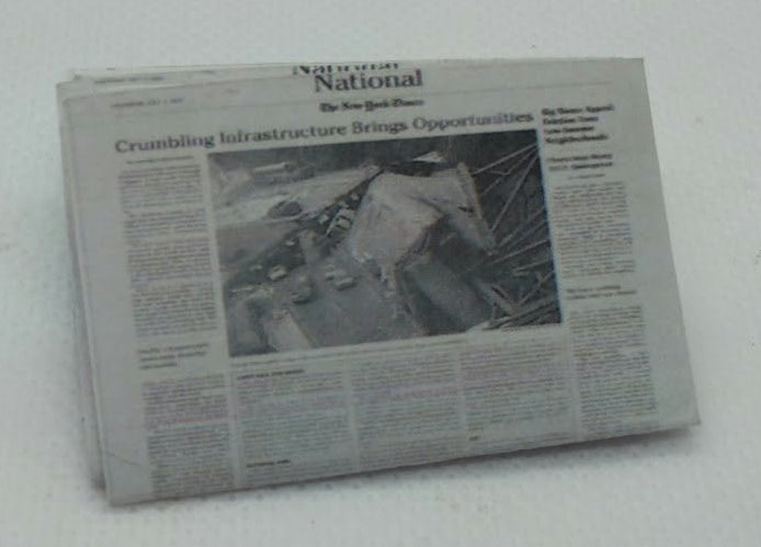 A miniature newspaper model, likely for scale models or dioramas, featuring a black and white photo on a white background.