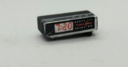 miniature clock radio in black with 7:20 on the digits. on a white background.