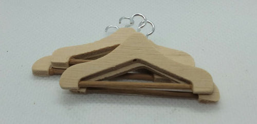 four miniature coat hangers on a white background.