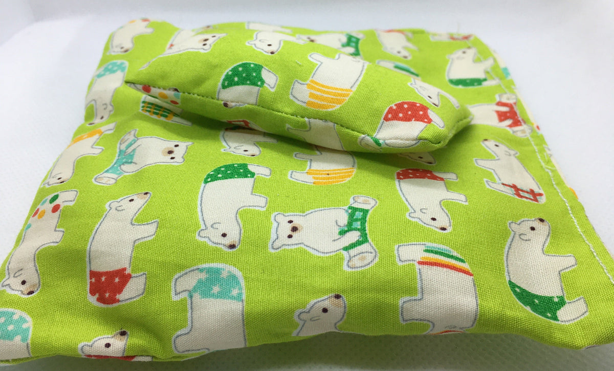 A duvet in miniature and a small pillow with a bright green background and a repeating print of white polar bears wearing colorful underwear, photographed on a plain white surface.
