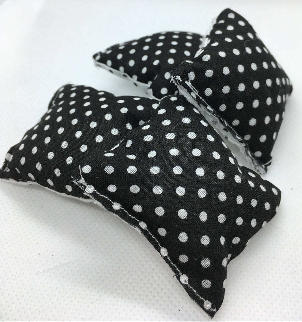 four cushions in miniature with a black and white polka dot pattern, displayed on a white textured surface.