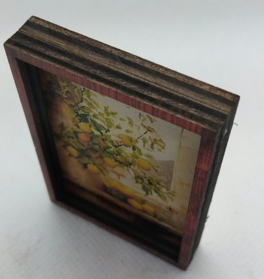 A small rectangular framed artwork with a dark brown wooden frame, showing a vintage-style floral or botanical print in muted yellow, green, and beige tones, photographed on a plain light background.