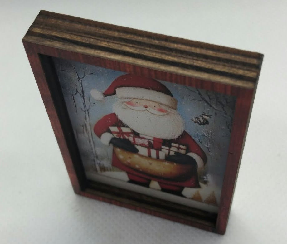 A small rectangular wooden picture frame with a Santa Claus illustration, photographed on a plain light  background.