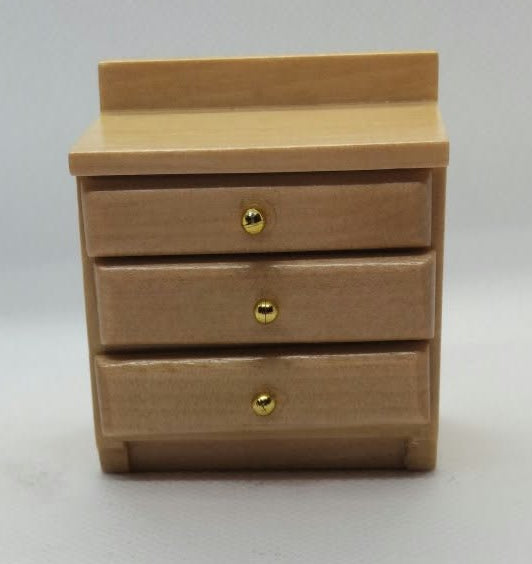 A miniature three-drawer wooden bedside  cabinet with small gold knobs, photographed against a plain white background .