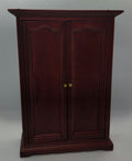 A dark reddish-brown wooden cabinet with two doors and small gold knobs, photographed against a plain light gray backdrop.